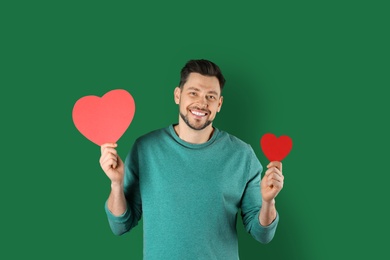 Portrait of handsome man with decorative hearts on color background