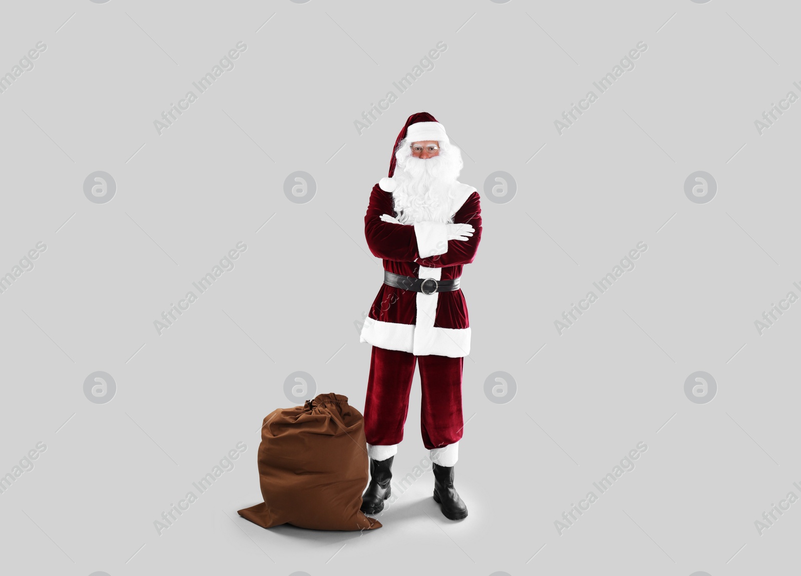 Photo of Full length portrait of Santa Claus with sack on light grey background