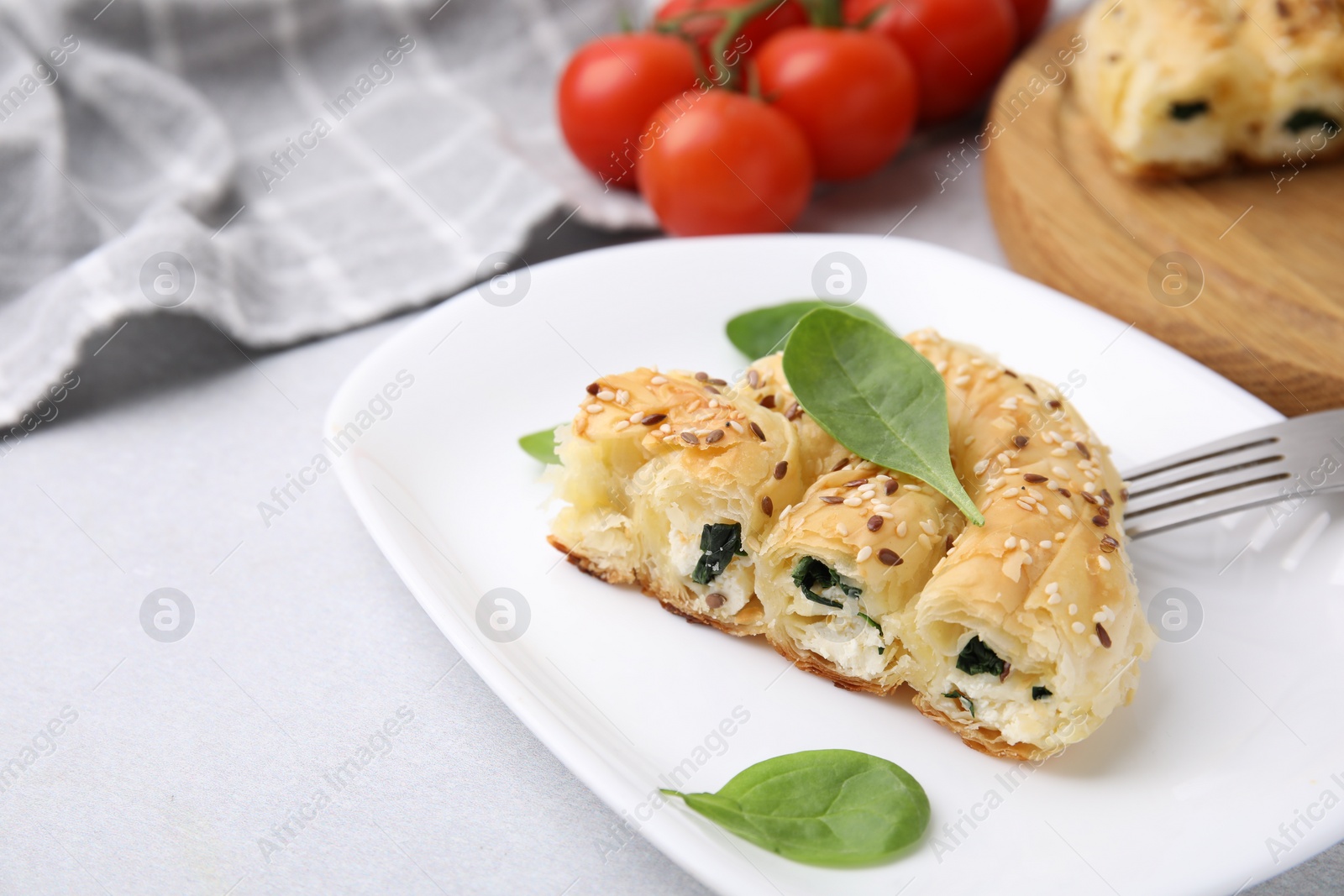 Photo of Piece of delicious puff pastry with spinach on light table