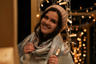 Young woman wearing warm sweater, hat and scarf  outdoors at night. Winter season