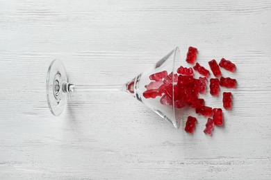 Photo of Martini glass with delicious jelly bears on wooden background, top view