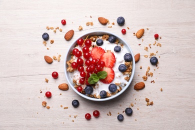 Photo of Delicious granola with fruits and nuts on wooden table, flat lay