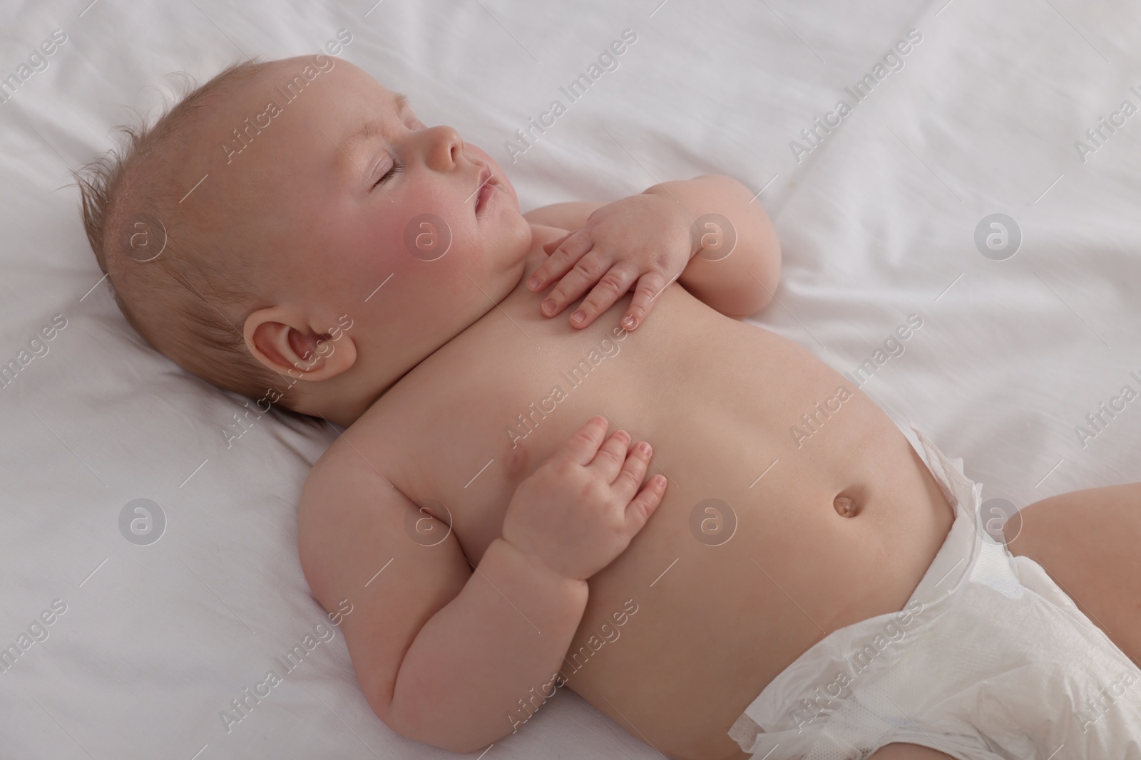 Photo of Cute newborn baby in diaper sleeping on bed at home