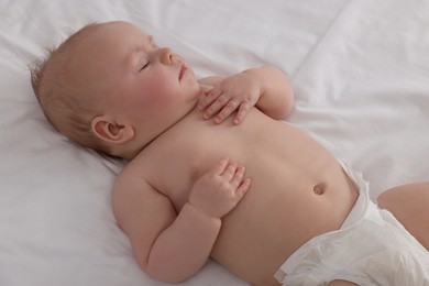 Photo of Cute newborn baby in diaper sleeping on bed at home