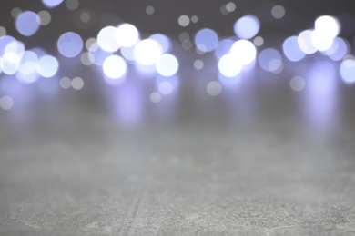 Blurred view of silver lights on grey table, space for text