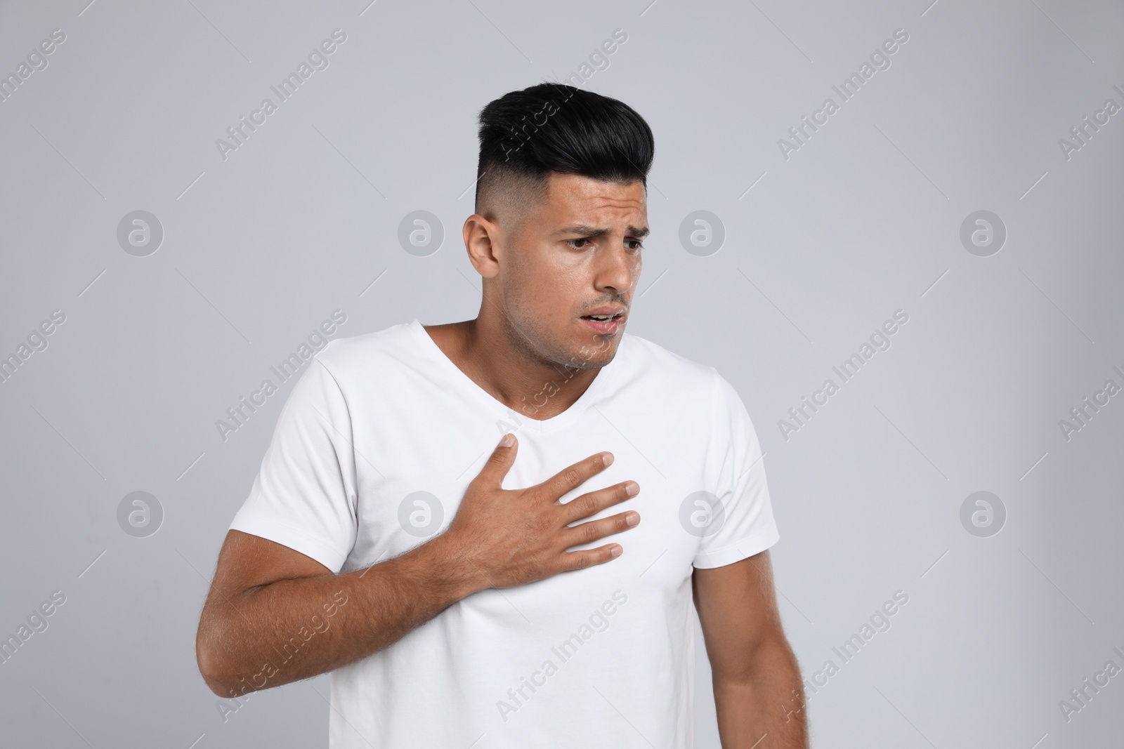 Photo of Man suffering from pain during breathing on grey background