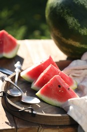 Photo of Slices of tasty ripe watermelon on wooden table outdoors
