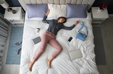 Photo of Exhausted woman sleeping fully dressed on bed at home, above view