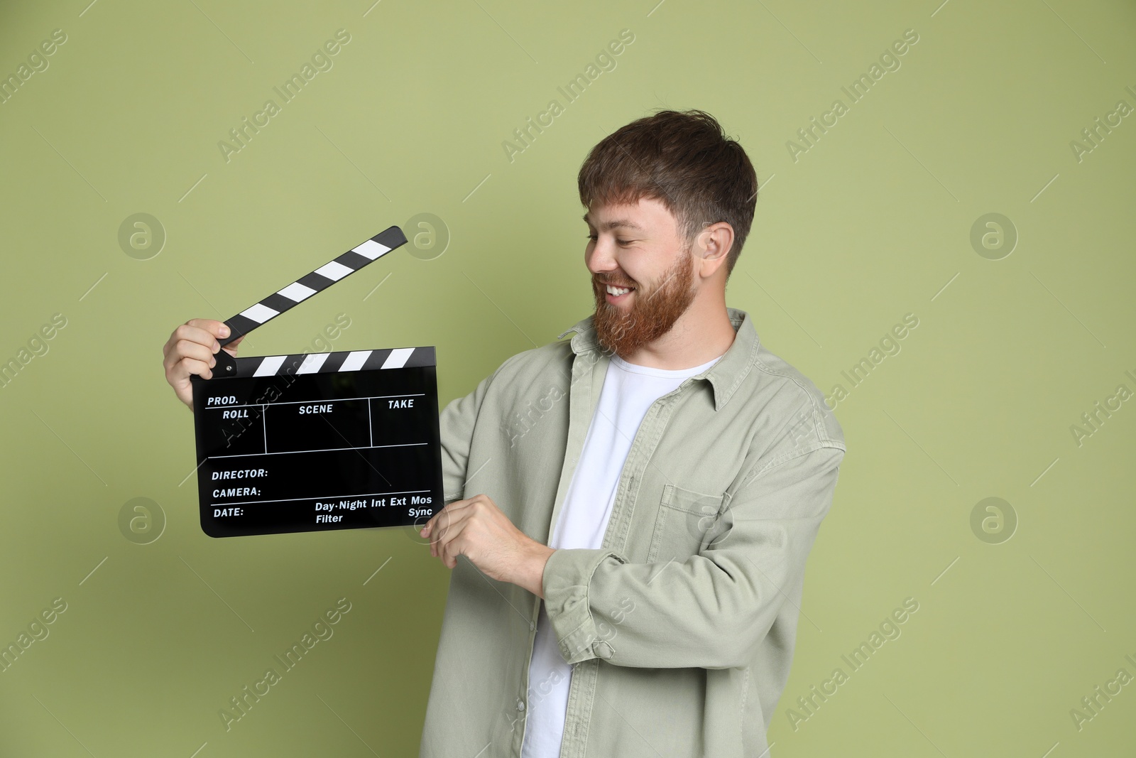 Photo of Making movie. Smiling man with clapperboard on green background