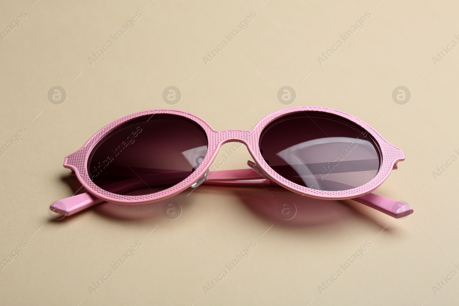 Photo of Stylish sunglasses on beige background. Fashionable accessory