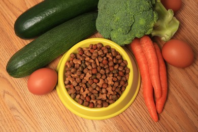 Dry pet food and products on wooden background, flat lay