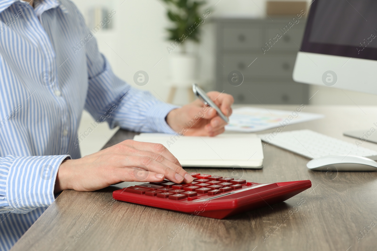 Photo of Professional accountant using calculator at wooden desk in office, closeup