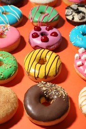 Sweet tasty glazed donuts on coral background