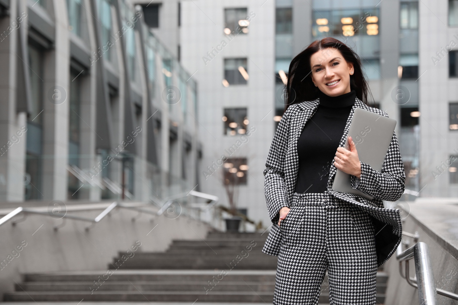 Photo of Beautiful woman in stylish suit with laptop outdoors. Space for text