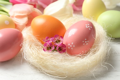 Photo of Sisal nest and painted Easter eggs on wooden table, closeup
