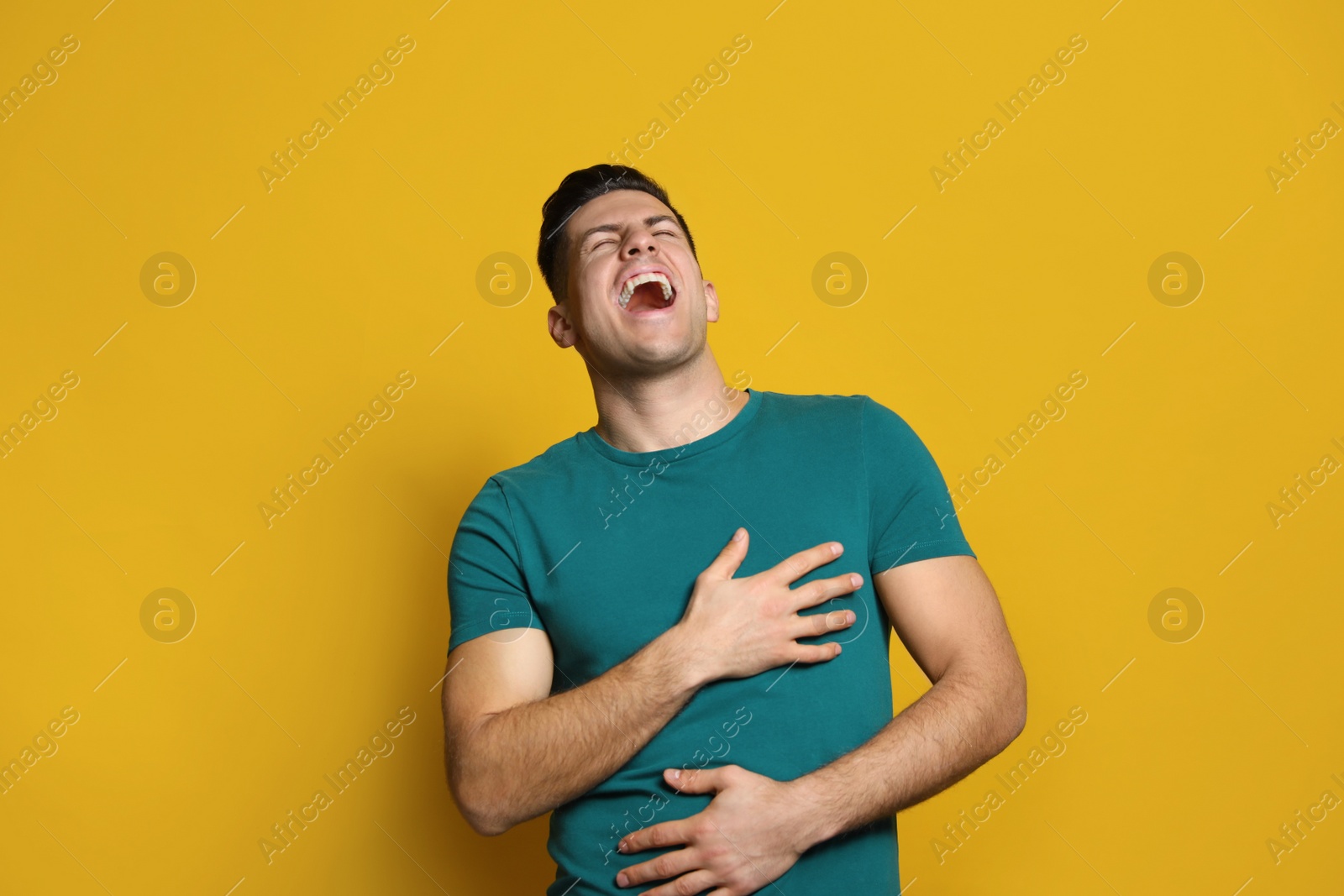 Photo of Handsome man laughing on yellow background. Funny joke