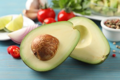 Fresh ripe avocado and other ingredients for guacamole on light blue wooden table, closeup