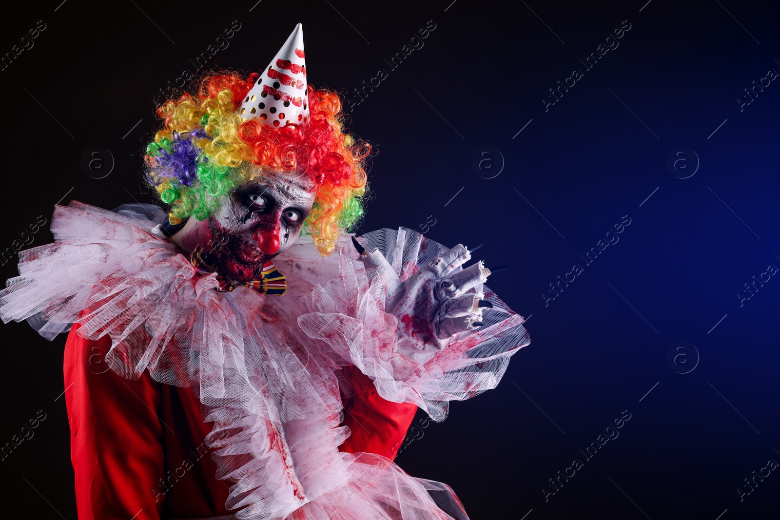 Photo of Terrifying clown on dark background, space for text. Halloween party costume