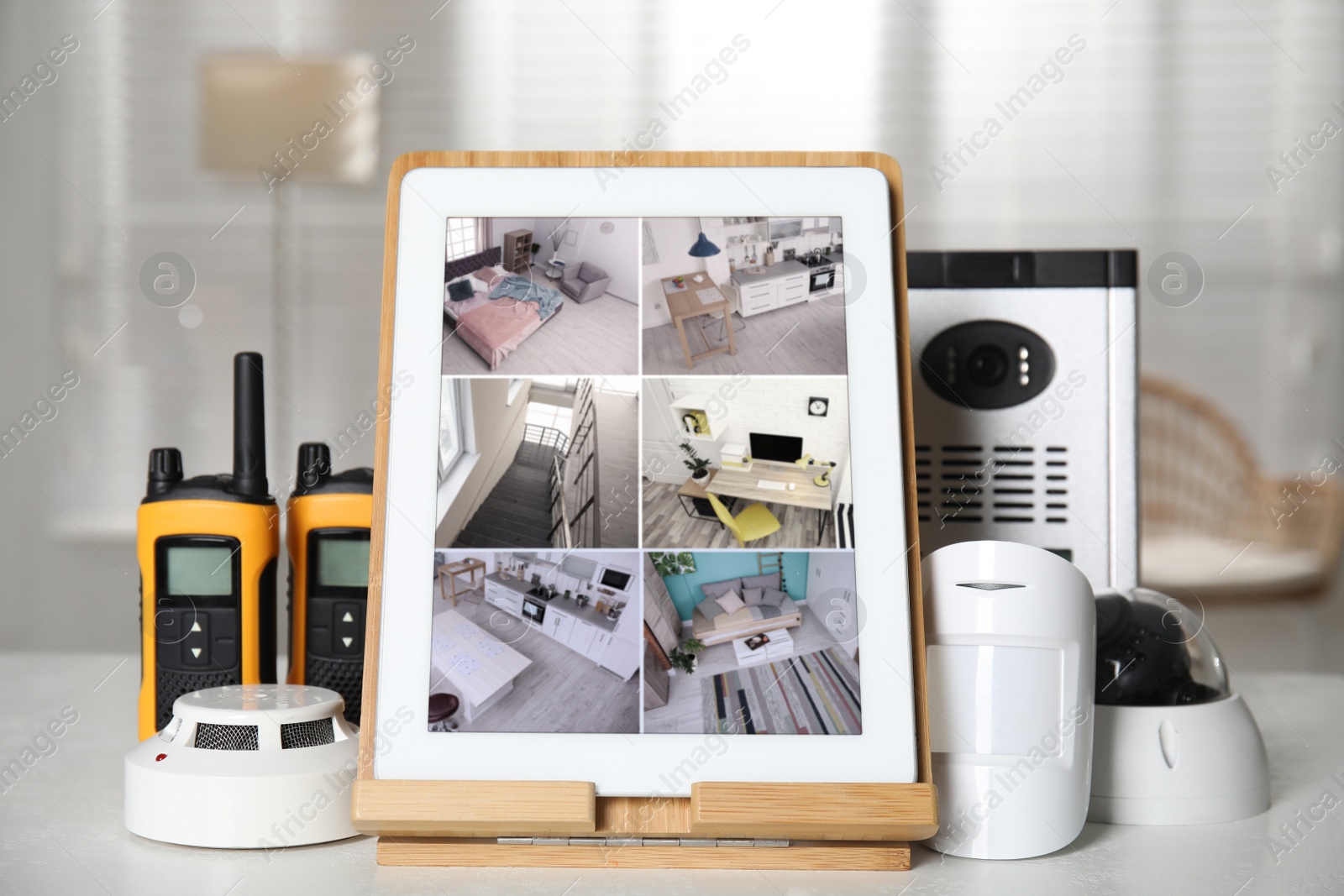 Photo of Tablet with view from CCTV cameras and different equipment for home security system on white table indoors