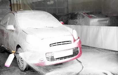 Cleaning automobile with high pressure water jet at car wash