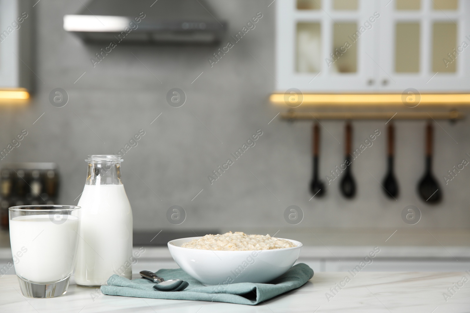 Photo of Breakfast time. Tasty oatmeal in bowl and milk on white marble table. Space for text