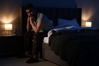 Photo of Frustrated man suffering from insomnia on bed