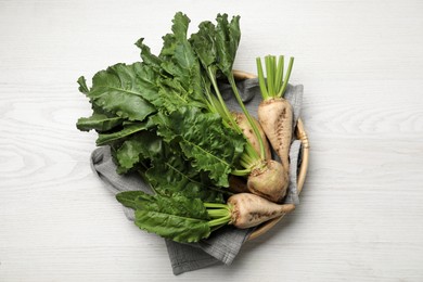 Basket with fresh sugar beets on white wooden table, top view