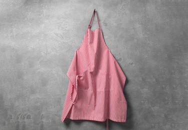 Clean red striped apron on grey tiled wall