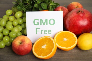 Photo of Tasty fresh GMO free products and paper card on wooden table