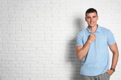 Photo of Portrait of handsome young man on white brick wall. Space for text