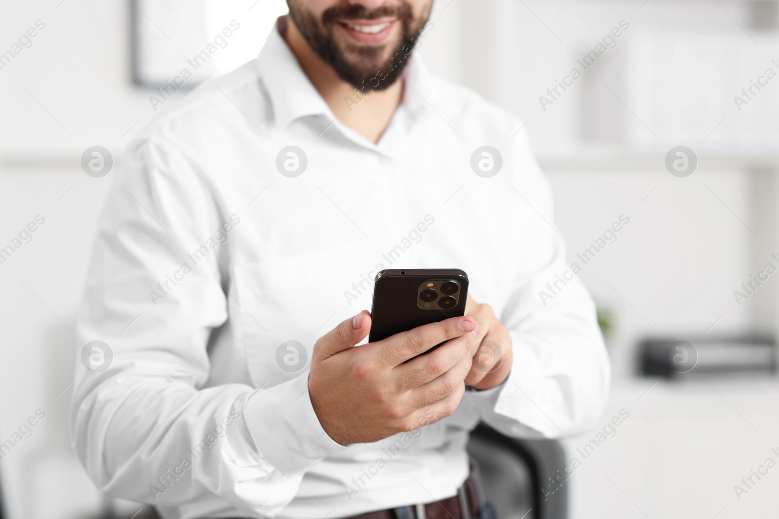 Photo of Young man using smartphone in office, closeup