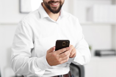 Young man using smartphone in office, closeup