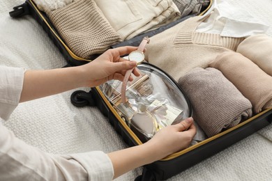 Woman packing suitcase for trip on bed, closeup