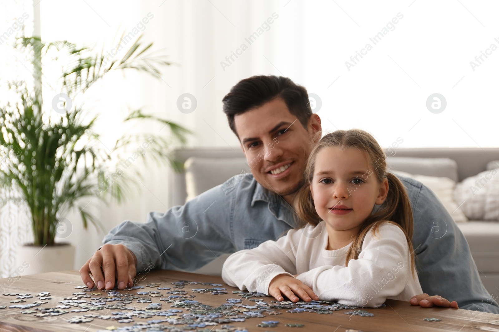 Photo of Man and his little daughter playing with puzzles at home