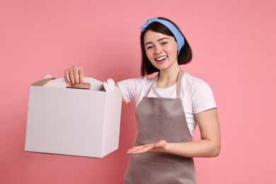 Photo of Happy confectioner with cake box on pink background