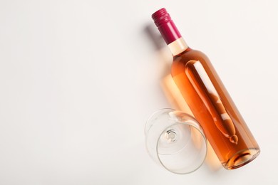 Photo of Bottle of expensive rose wine and wineglass on white background, top view. Space for text