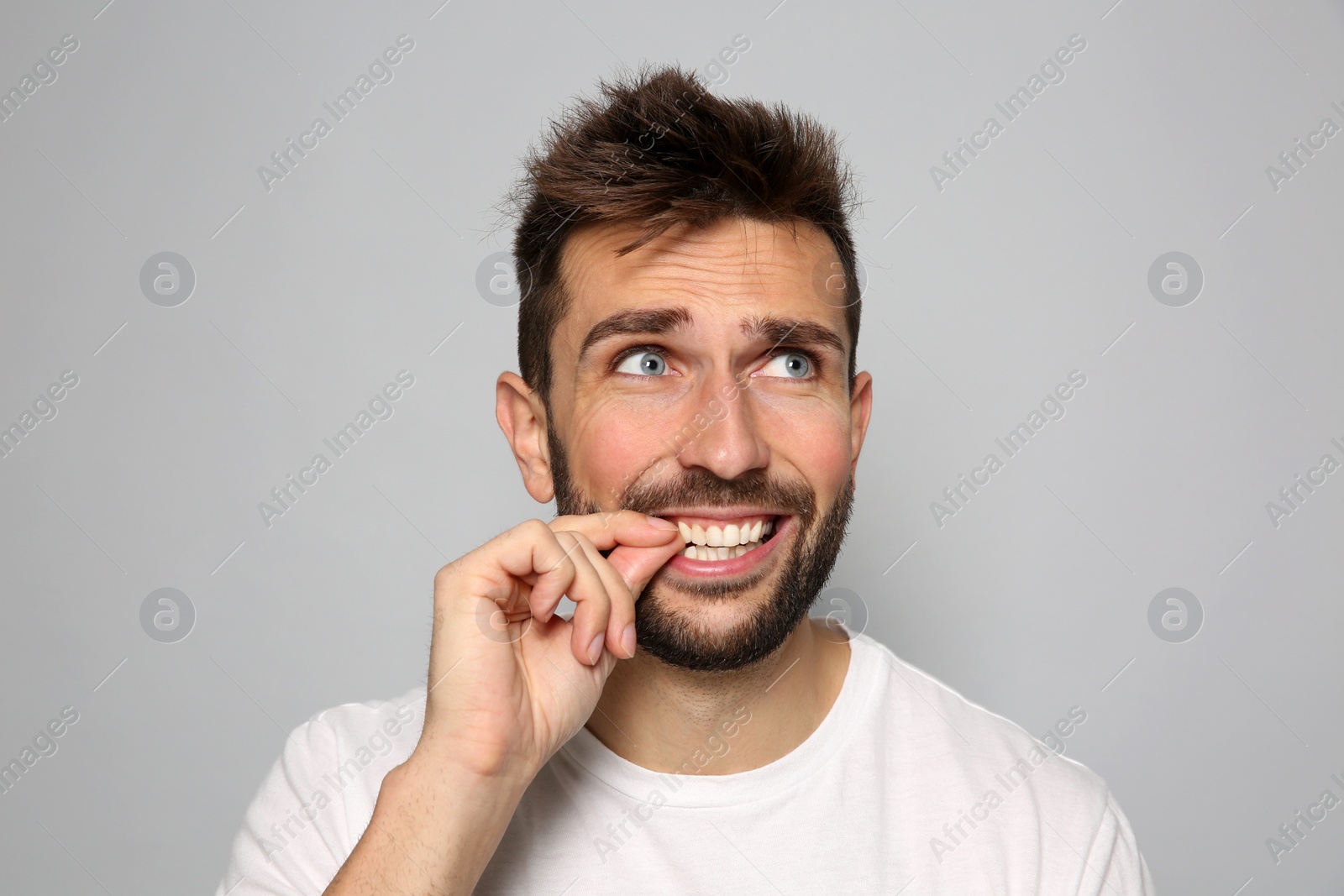 Photo of Man biting his nails on grey background