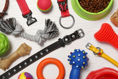 Photo of Flat lay composition with dog collars, toys and food on white wooden table