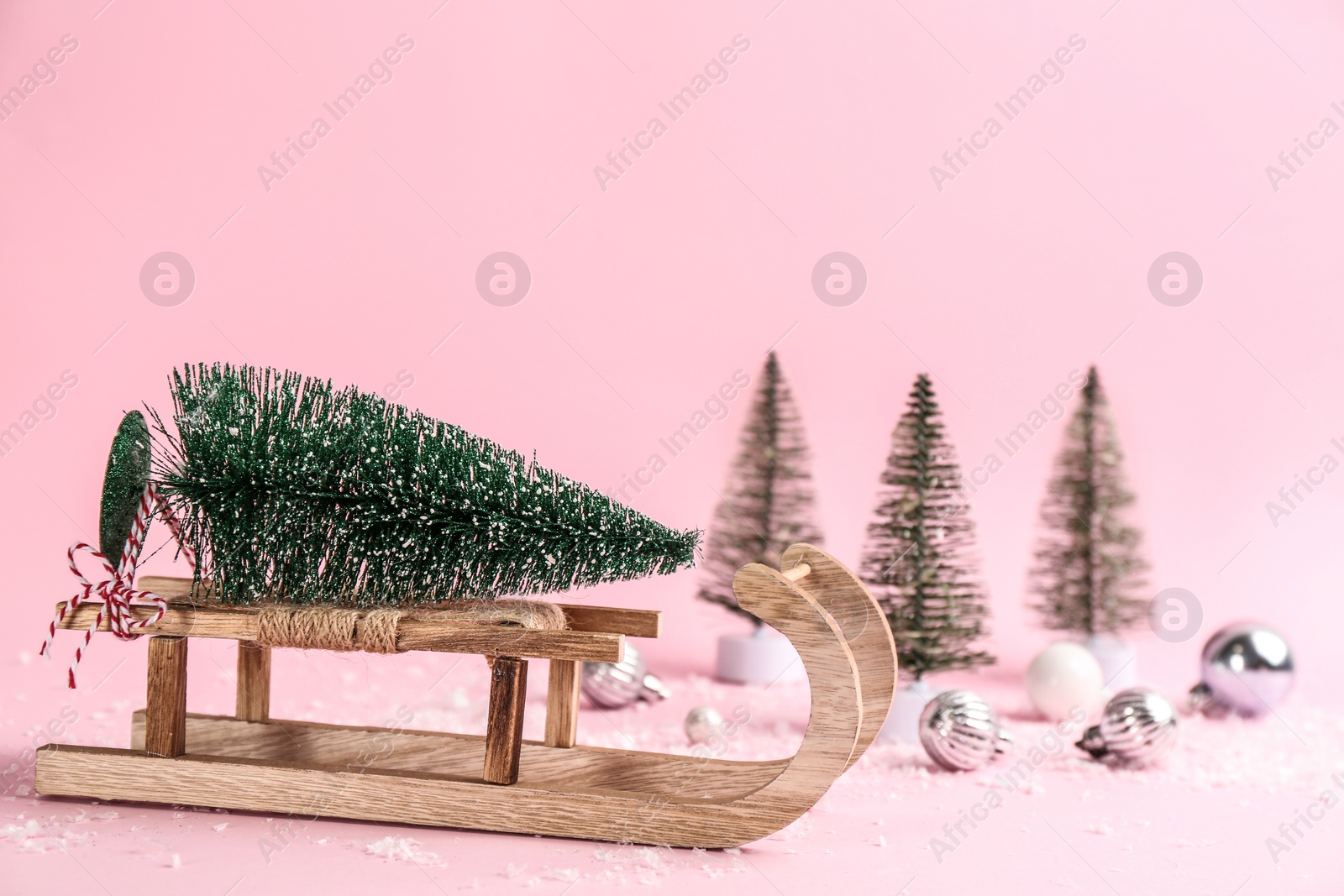 Photo of Beautiful Christmas composition with miniature sleigh on pink background