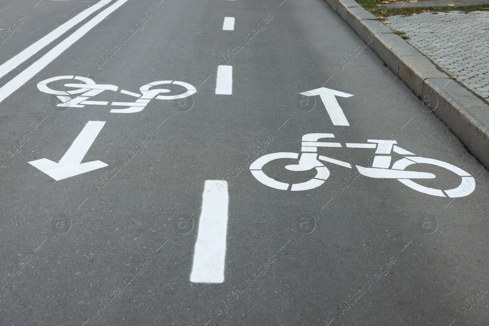 Photo of Two way bicycle lane with white signs on asphalt