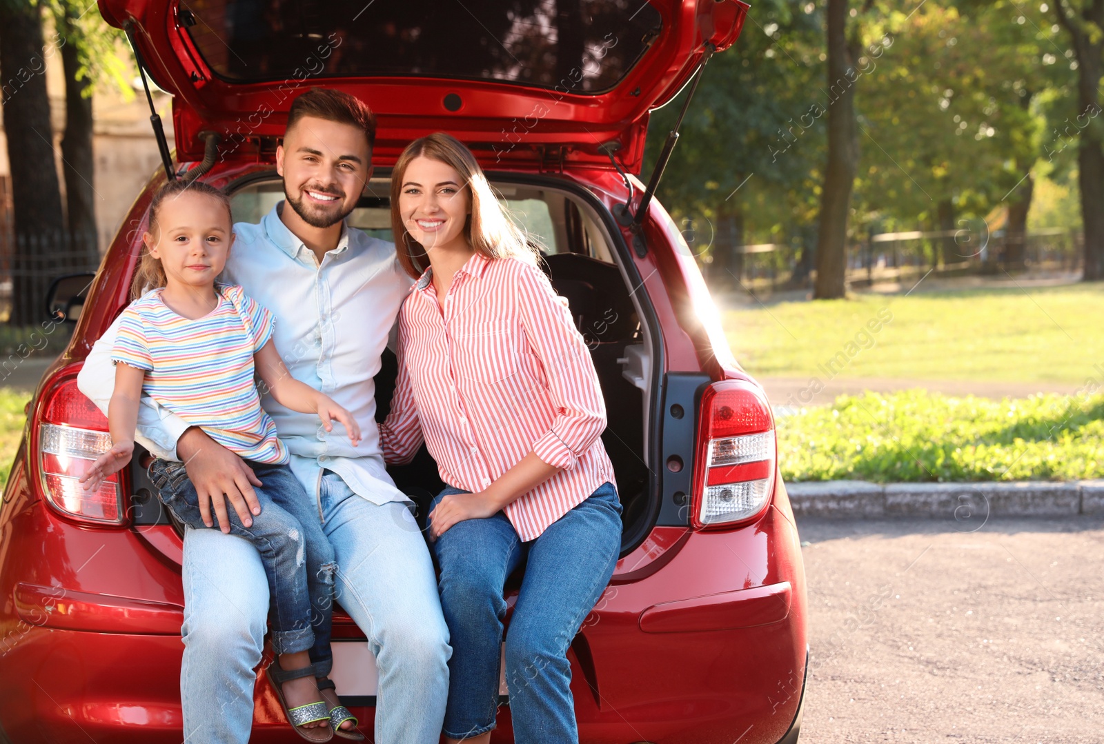 Photo of Happy family sitting in car's trunk outdoors