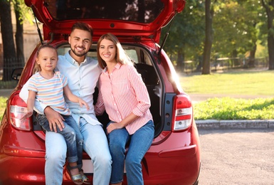 Happy family sitting in car's trunk outdoors