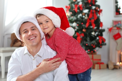 Father and child in Santa hats celebrating Christmas at home