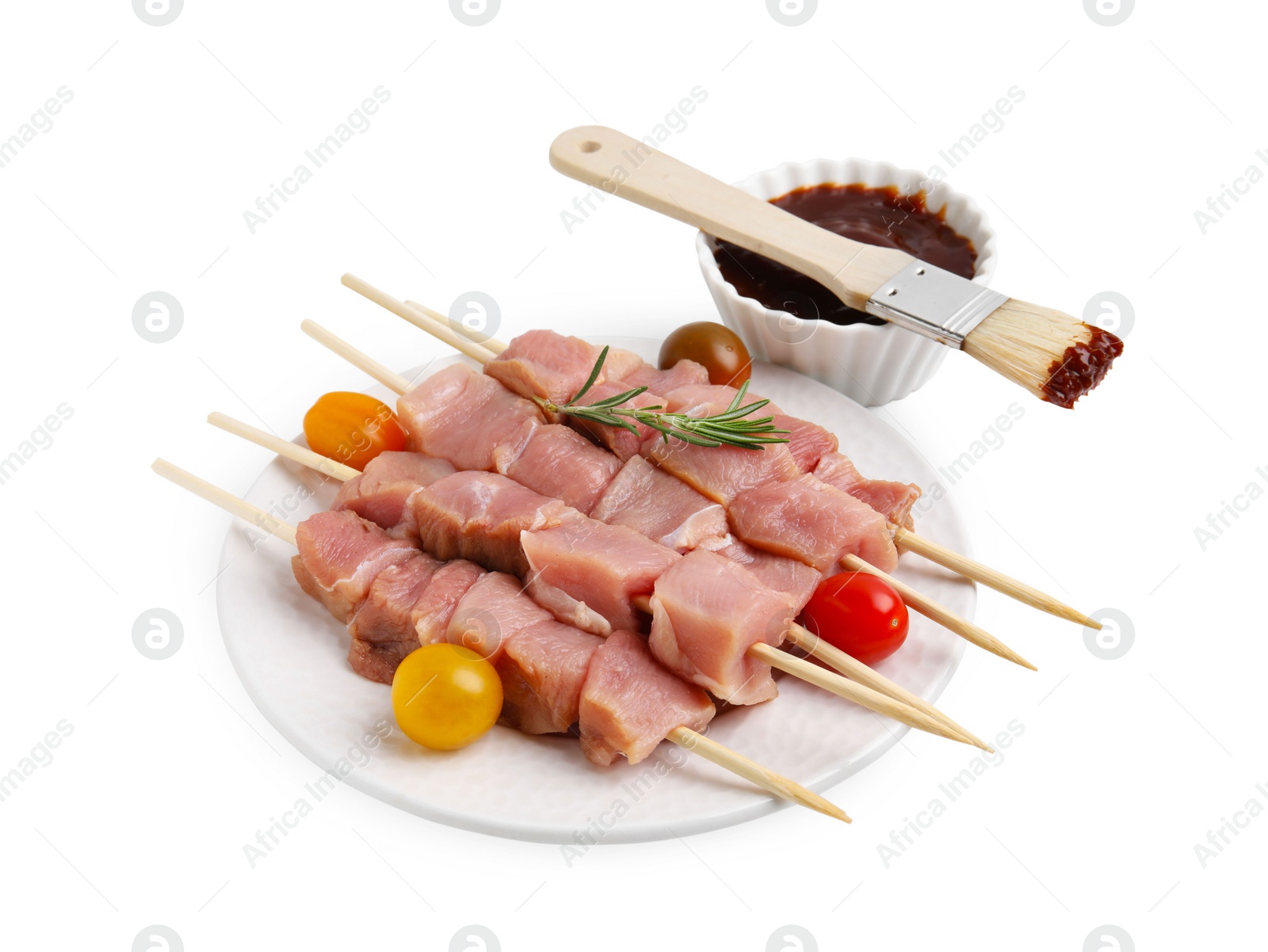 Photo of Skewers with pieces of raw meat, rosemary, tomatoes and marinade isolated on white