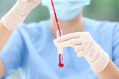 Photo of Scientist dripping blood into test tube in laboratory