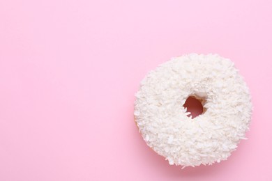 Photo of Tasty glazed donut with coconut shavings on pink background, top view. Space for text