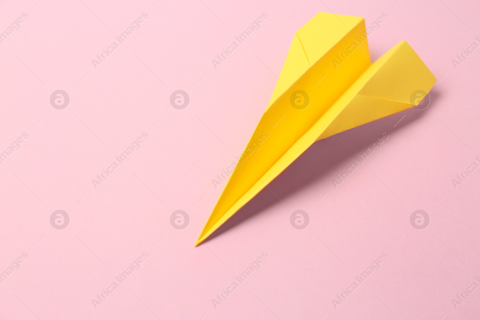 Photo of Yellow paper plane on pink background, space for text