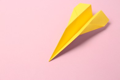 Yellow paper plane on pink background, space for text