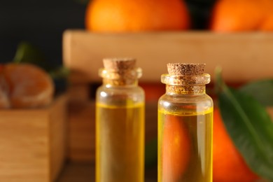 Photo of Bottles of tangerine essential oil on blurred background, closeup