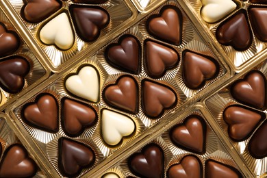 Photo of Beautiful heart shaped chocolate candies in box as background, top view